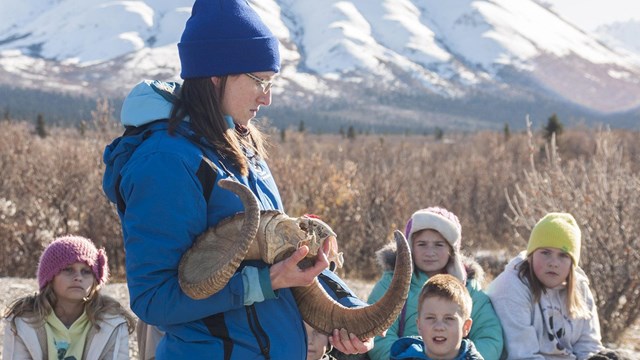instructor holds dall sheep horns as children sit and listen