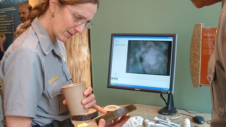 female ranger looks at an item with a visitor