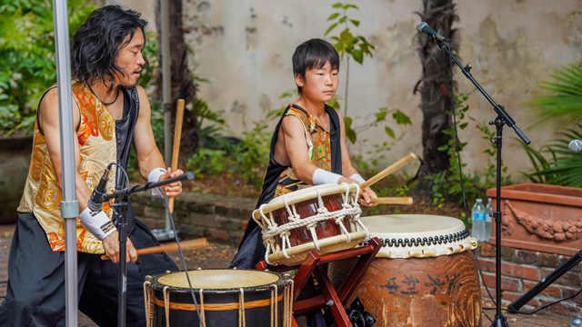 A father and son percussionist drumming in French Quarter courtyard