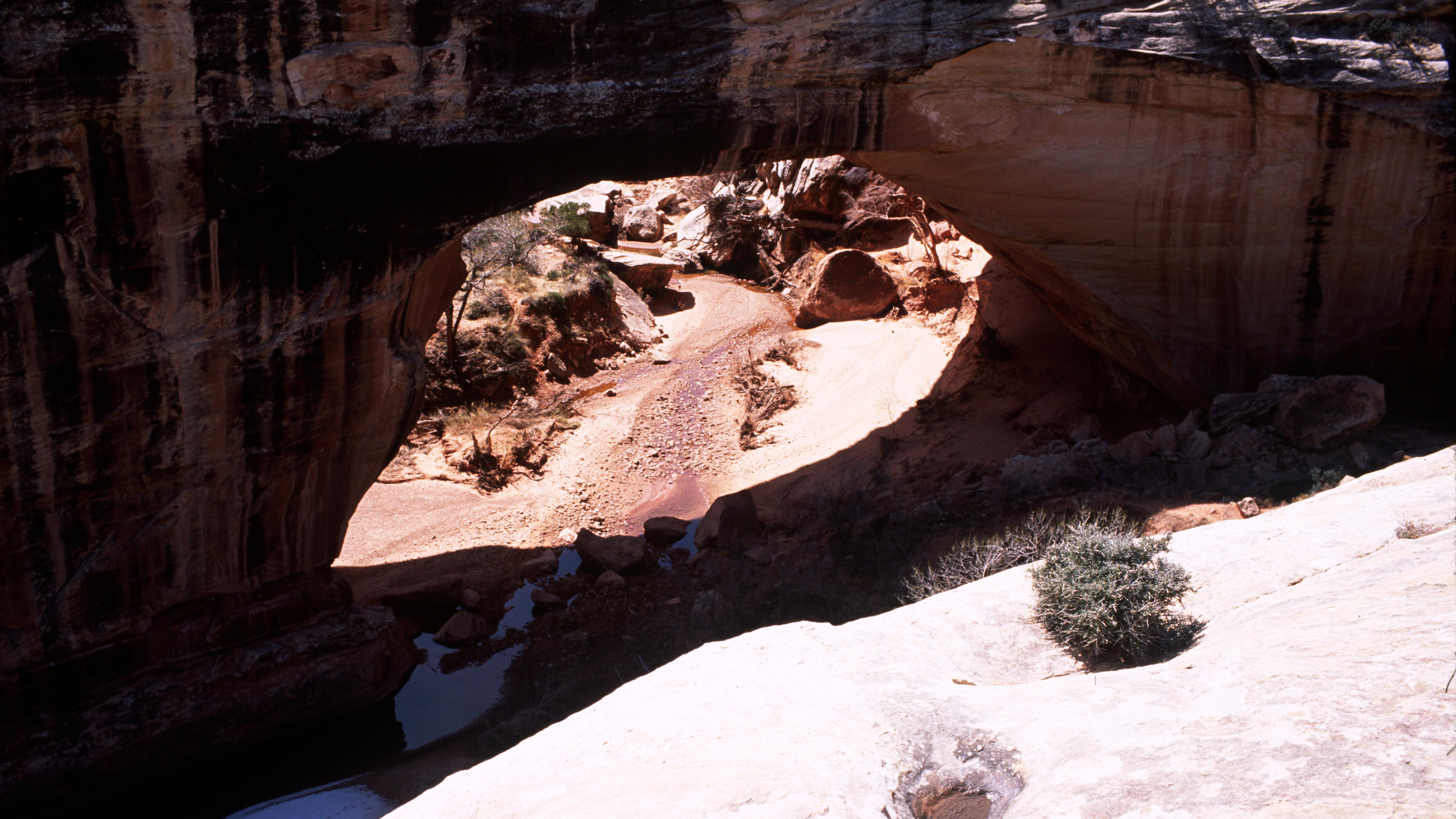 Silhouetted natural bridge with sunlight under the bridge and on the rock