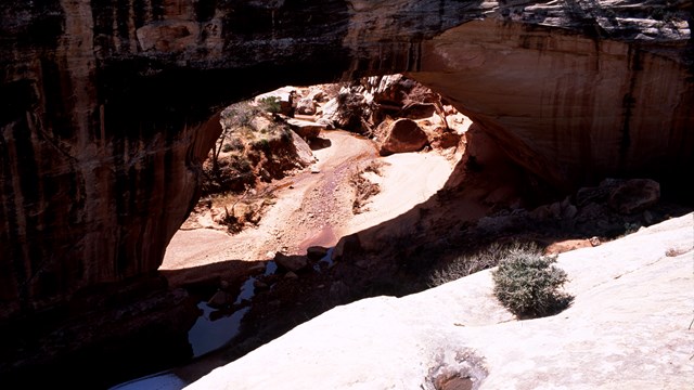 Silhouetted natural bridge with sunlight under the bridge and on the rock