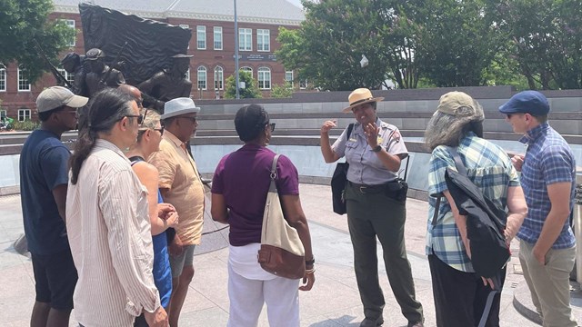 Park ranger talking to a group of visitors in front of a statue of soldiers