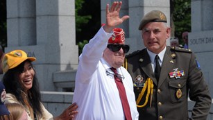 World War II veteran waving to crowd at World War II Memorial