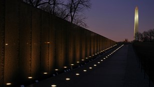 Vietnam Veterans Memorial at night, with Washington Monument in the background