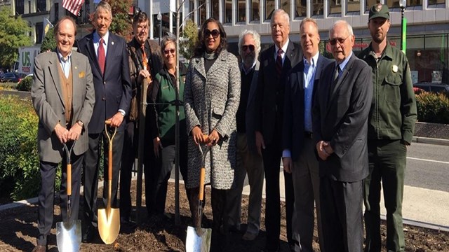 Men and women stand with shovels during a groundbreaking ceremony.