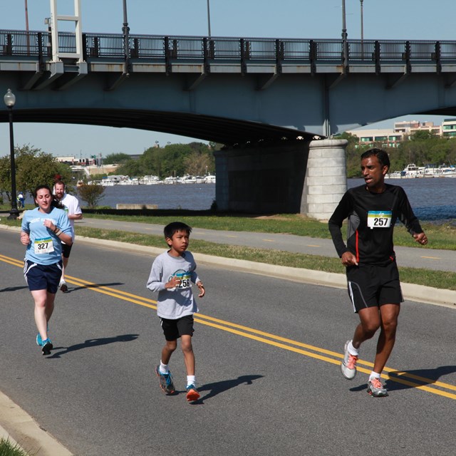 People wearing race bibs running on a road