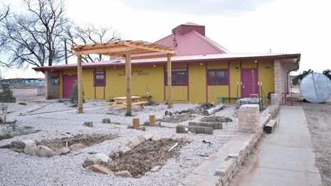 View of Klagetoh Chapter House - yellow and red painted entrance as seen from stone path
