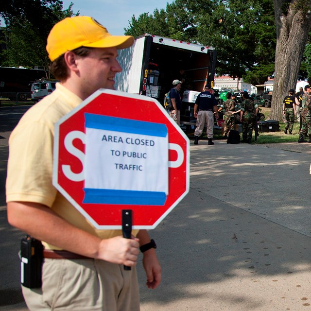 A volunteer showing visitors that the area is closed with a sign.