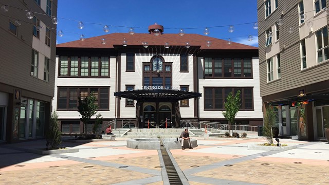 Courtyard leading to the entrance of a two-story school. Double entrance doors with overhang