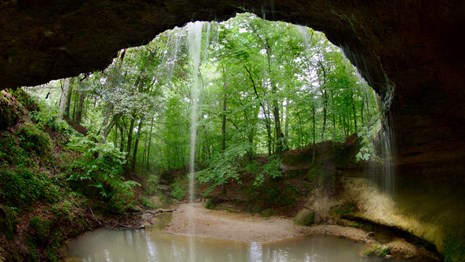 A view from inside a cave-like area with water dripping from the top of the entrance. 