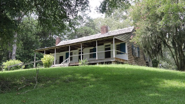 A cabin on a hill with trees all around.