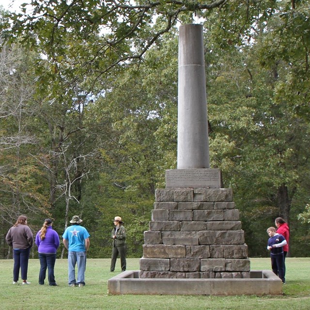 A stone monument with a shaft and people taking pictures
