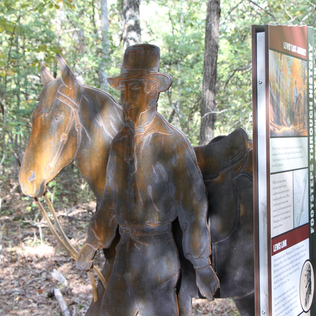 A rusty statue of a man walking a horse.