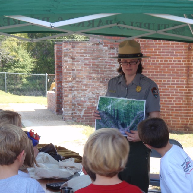 A park ranger showing young students a photo of the heavily eroded sunken trace trail.