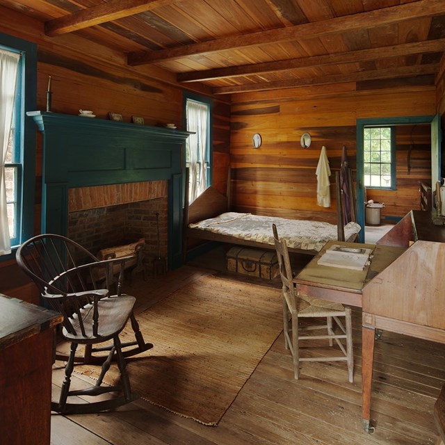 The inside of a wooden walled room with rustic furniture.