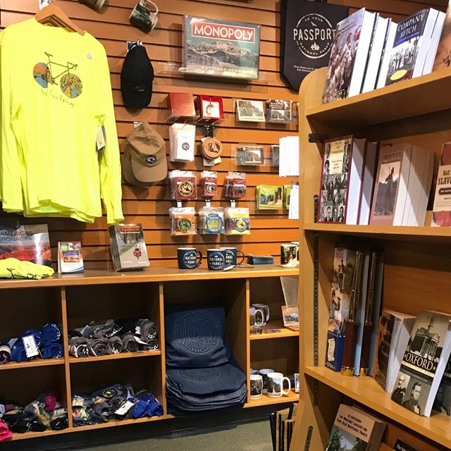 A store with books on a shelf, shirts, hats, and cups.