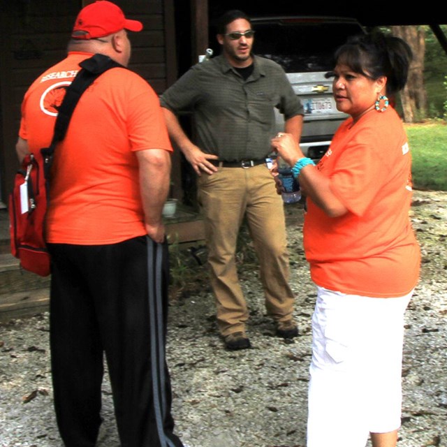 A group of American Indians in orange t-shirts and casual trousers. 
