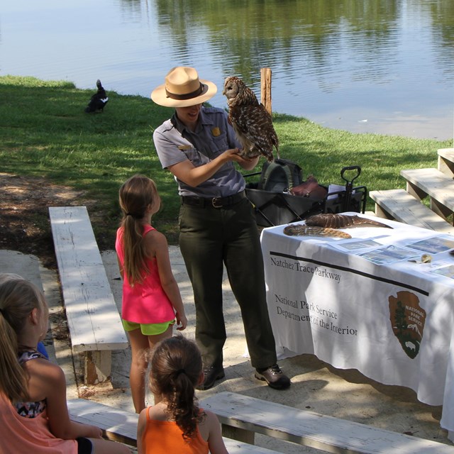 A ranger shows a mounted owl to a junior ranger.