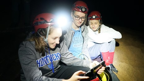 3 young women control a remote submarine in a cave