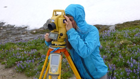 A person wearing a blue rain coat looks through a yellow transit