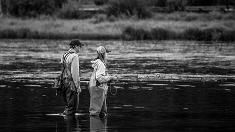 black and white photo of a father and daughter fly fishing in a lake 