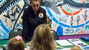 Three children listen to an NPS employee