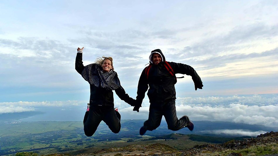 two people jump in the air with smiles on their faces