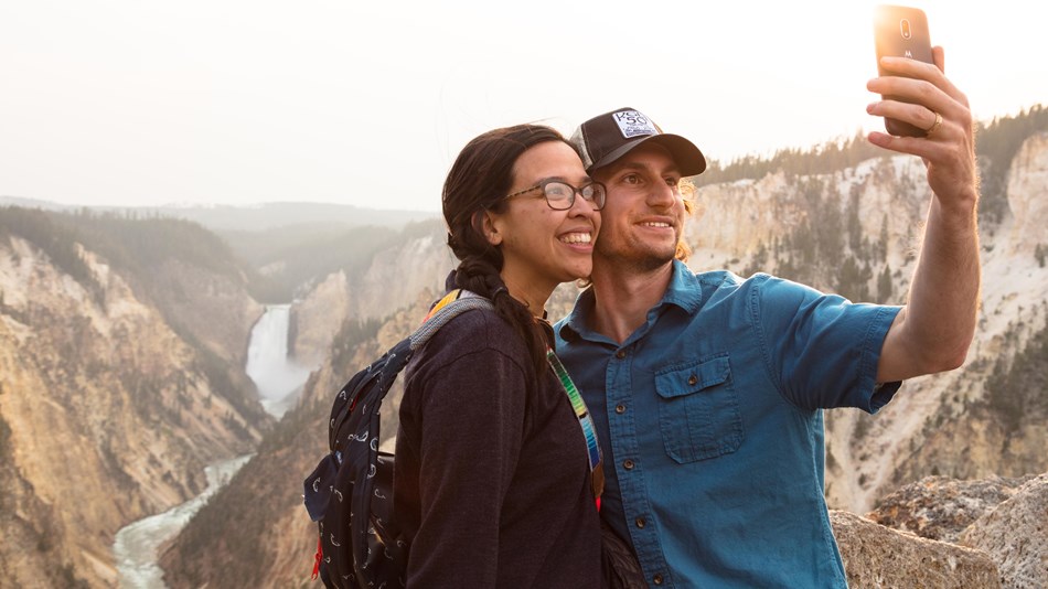2 hikers take a safe selfie with canyon and river in the background