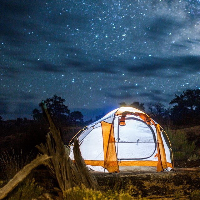 two glowing tents under a starry night sky