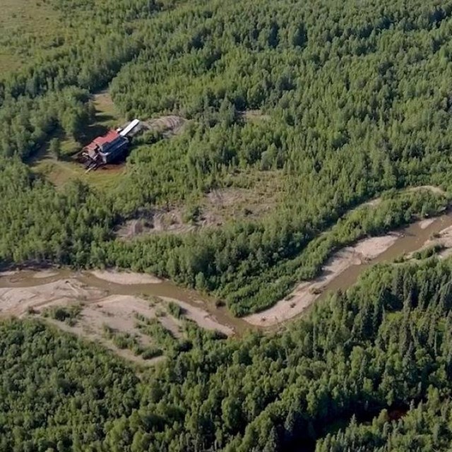 an ariel shot of a winding creek and a historic mining building