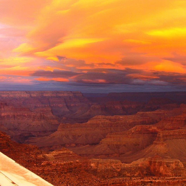 a brilliant yellow and orange sunrise over the grand canyon