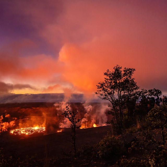 a glowing lava lake at sunset with a group of people observing from a cliff above