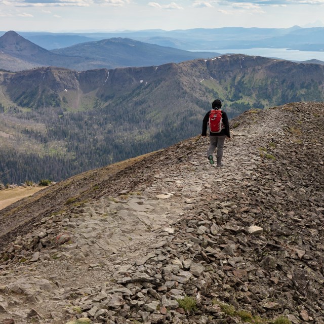 A person hikes on a a designated trail of rocks on a mountain