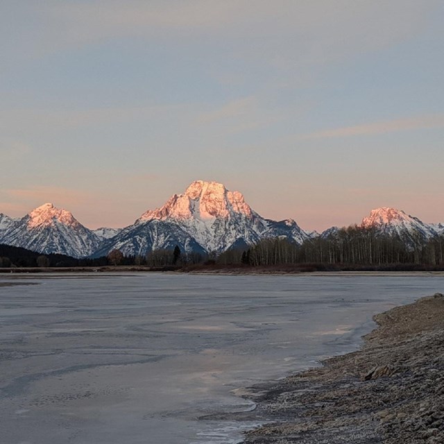 pink sunrise kisses the snowy tops of the Teton mountain range