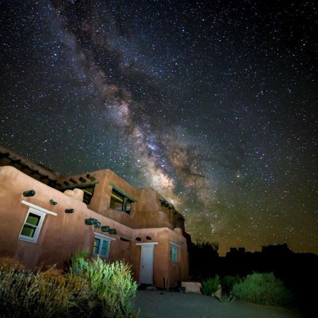 the milky way and starry night sky above an adobe style building at night