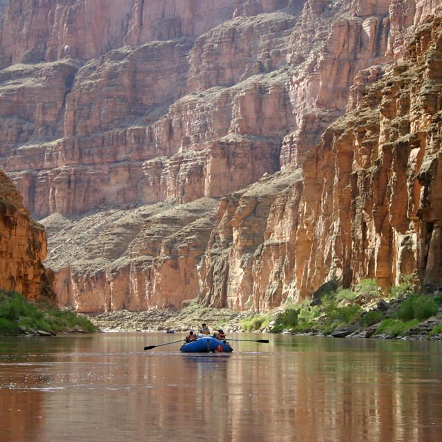 rafters float down a calm portion of the colorado river within the grand canyon