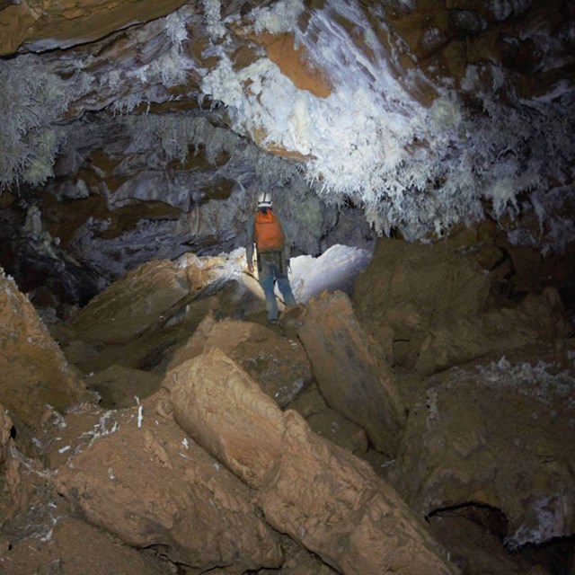 a caver illuminates white cave formations with their headlamp