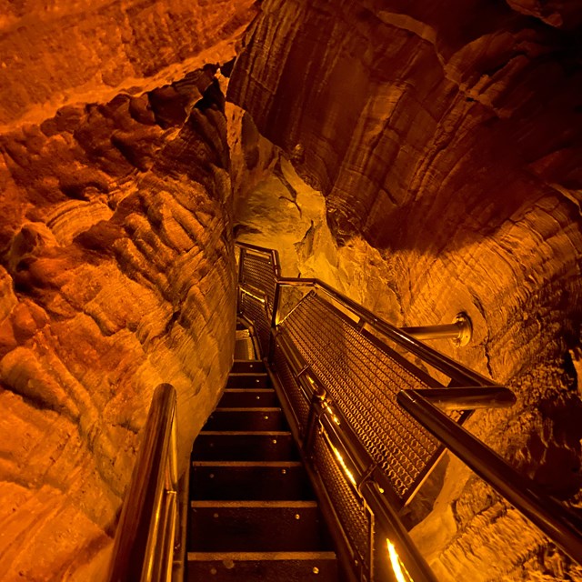a steep staircase in a cave lit up by orange light