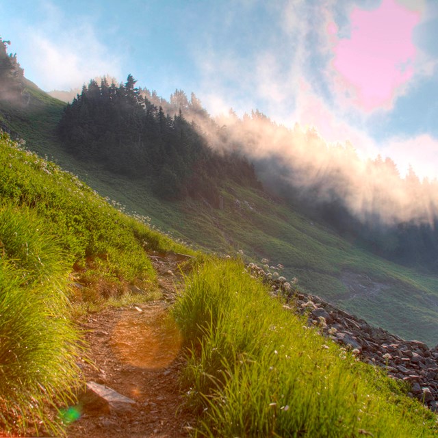 sun shines on a grass hill in a mountain pass 