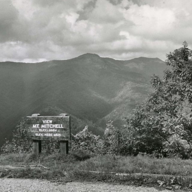 a historic photograph of a mountain view with sign that says 