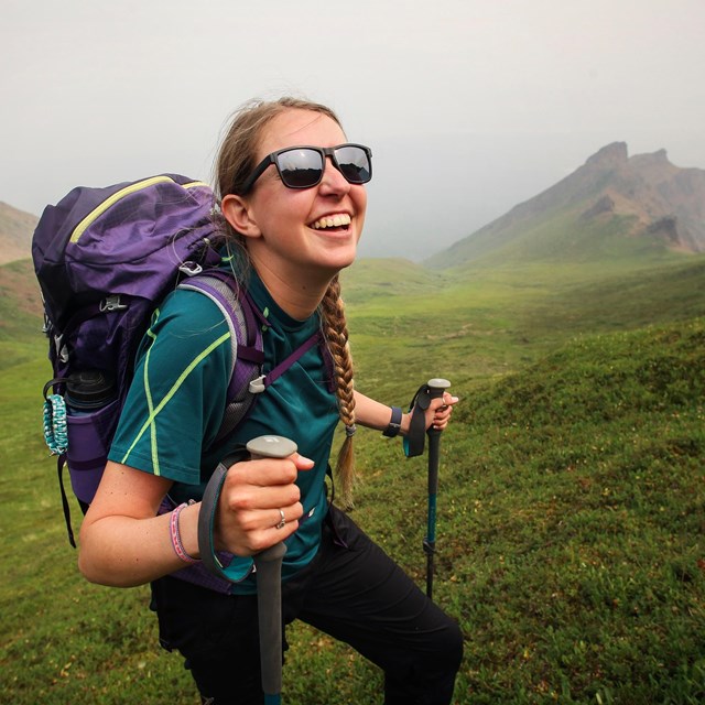 a smiling hiker with sunglasses and a backpack