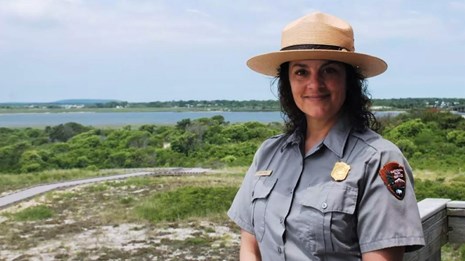 A park ranger in tan ranger hat and grey-blue short-sleeved NPS collared button-down