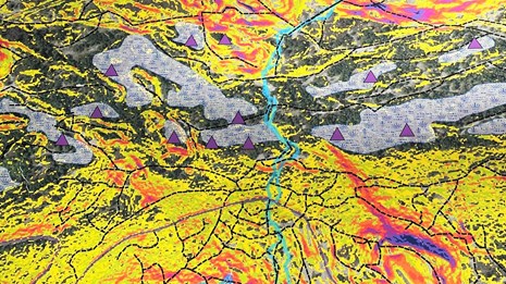 Closeup of a vibrant map with areas of yellow, purple triangle markers and a light blue river