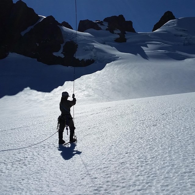 Scientist probing a glacier to measure depth of snow