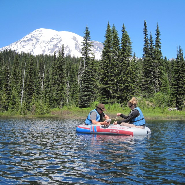 Two people in rubber raft collecting data in a lake at Mount Rainier