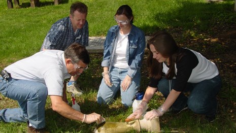 Four people cleaning stone carving in cemetery