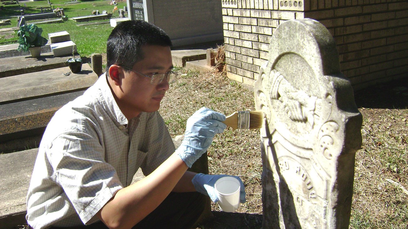 Hybrid plastics researcher, Bruce Fu, applies a stone strengthener to a historic marble grave marker