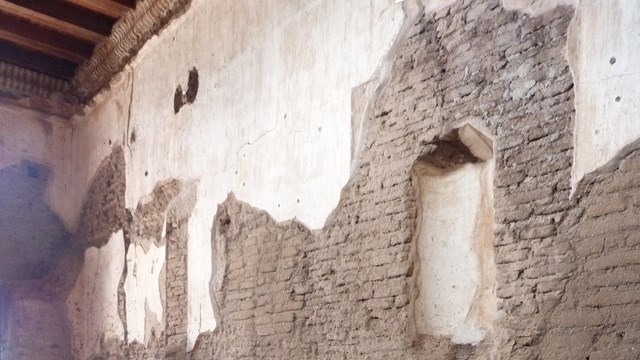 Interior of mission church nave with roped off side altar remnant and niche above