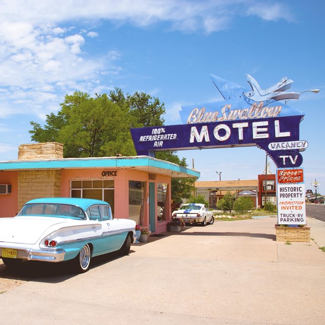 A neon hotel sign: a larger than life blue bird above text reading Blue Swallow Hotel.