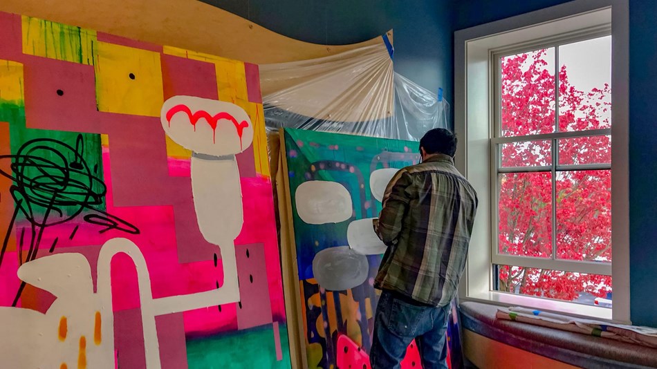 Nick Mello painting a large vibrant mural